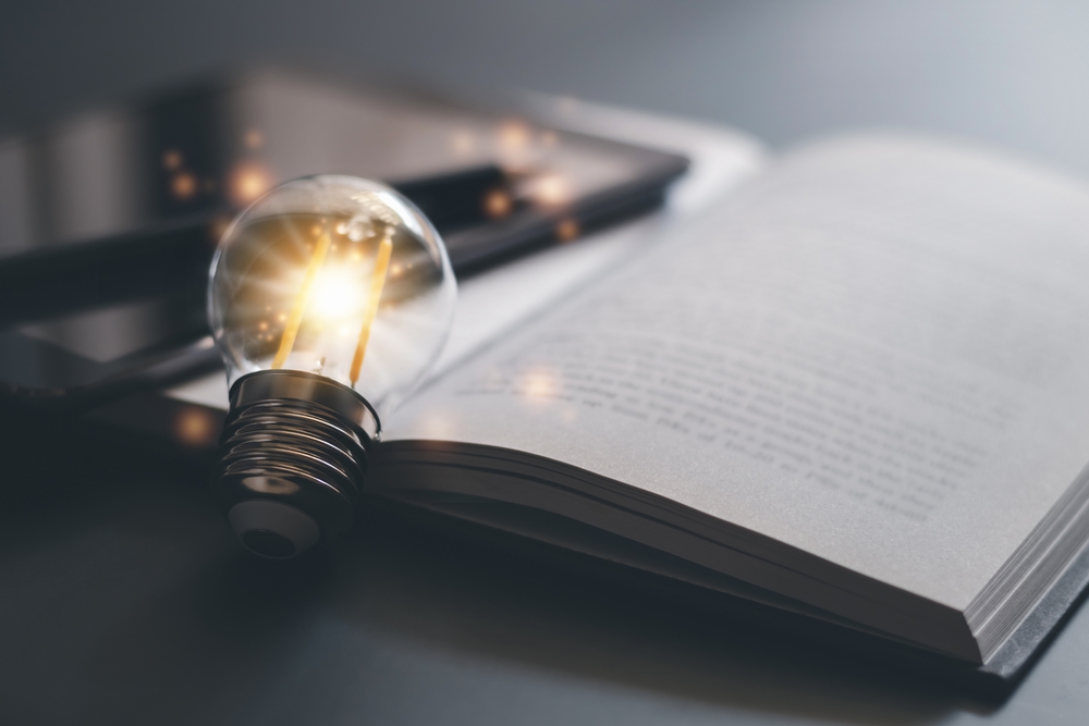 A lit lightbulb resting on a book